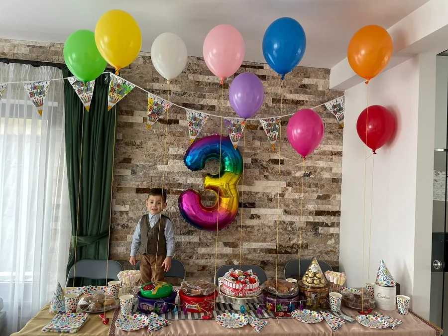 3rd birthday celebration with colorful balloons and a sweets table